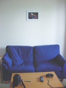 Ikean pöytä ja sininen sohva, seinällä siltaa esittävä valokuva