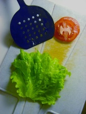 Salaatinlehti ja pari tomaattisiivua leikkuulaudalla