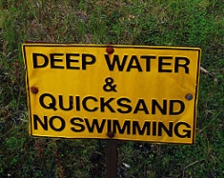 Juoksuhiekasta ja syvistä vesistä varoittava kyltti