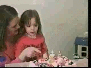 Pikkutyttö puhaltaa synttärikakun kynttilän sammuksiin kenenkään häiritsemättä