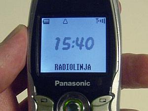 Panasonic-merkkisen puhelimen sinertävällä taustavalolla valaistu näyttö, jossa kellonaika 15:40 (ja teksti 'Radiolinja' kapiteelikirjaimin)
