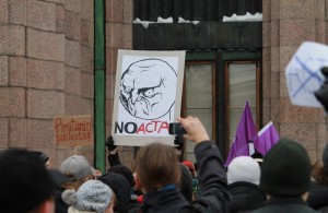 Kylttejä Stop ACTA -mielenosoituksessa Helsingin rautatieaseman edustalla. "Piratismin puolesta?" ja "NO ACTA", taustalla Piraattipuolueen lippuja.